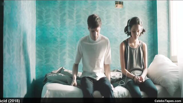 Hot Russian teen girl with headphones sits with guy on bed in erotic movie scene