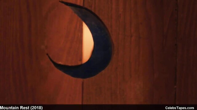 Natalia Dyer moon-shaped cutout in dark wood door nude scene