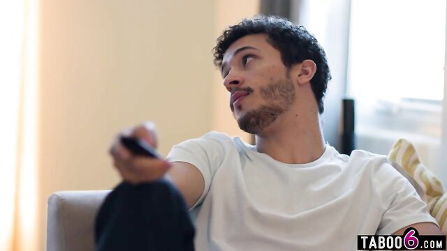 Handsome Arab guy with remote on couch in taboo scene