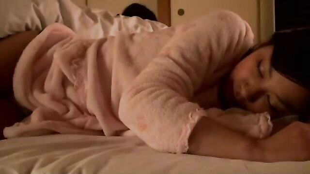 Asian stepmom in pink bathrobe sleeping nude on bed in hotel