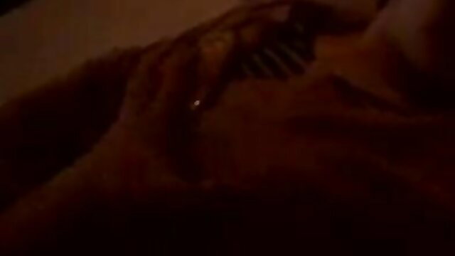 Blurry closeup of woman's hand stroking hard cock in dim light