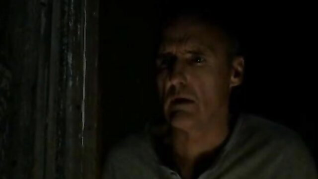 Bald middle-aged man stares intensely in dark scene, stepdad vibe