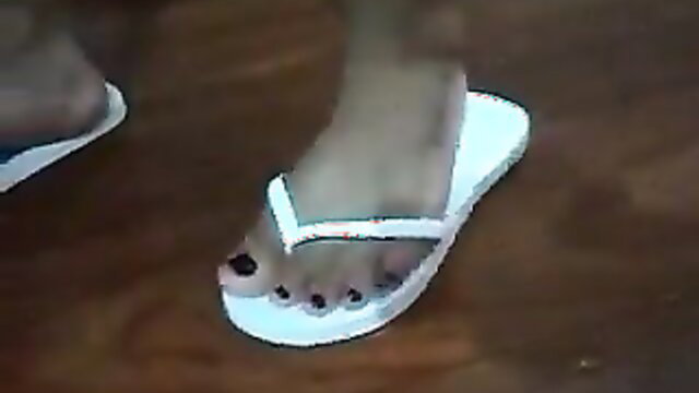 Latin woman's sexy feet in white flip flops, dark toenails