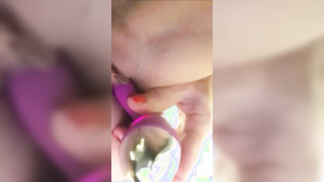 Blurry closeup of woman's face and hand holding purple glass butt plug