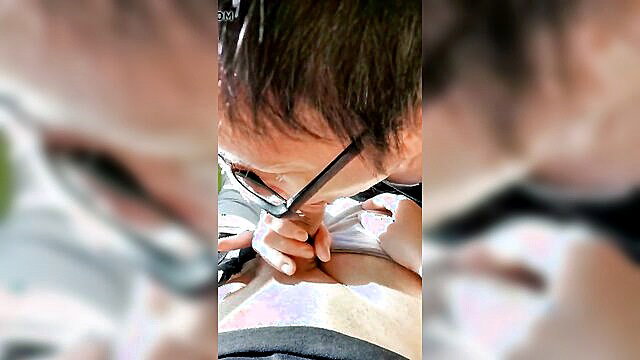 Asian man in glasses tattoos woman's chest closeup in amateur video