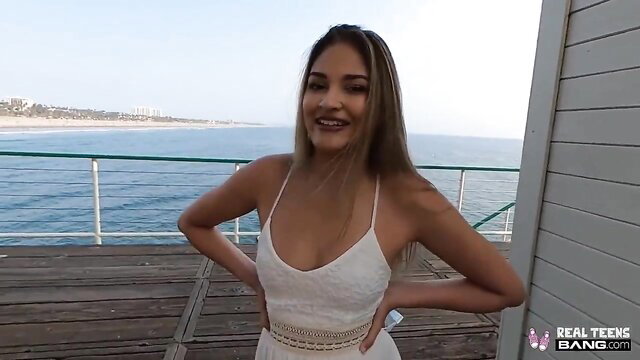Gizelle Blanco in white lace dress on beach pier, Hawaiian Latina tease