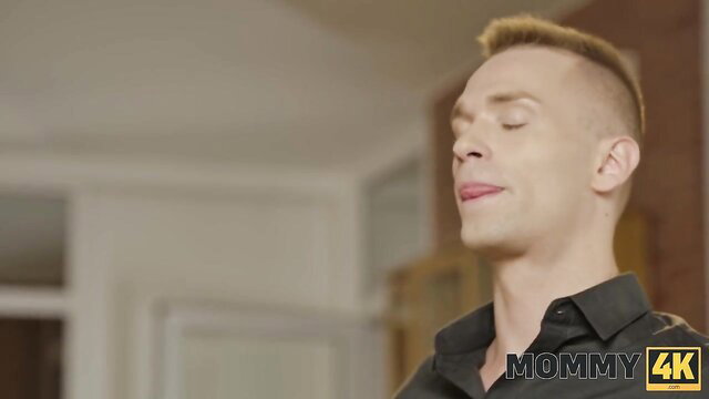 Blond man with buzzed hair smirks eyes closed in Mommy4K hotel scene