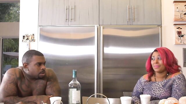 Muscular black man and curvy redhead beauty at kitchen table