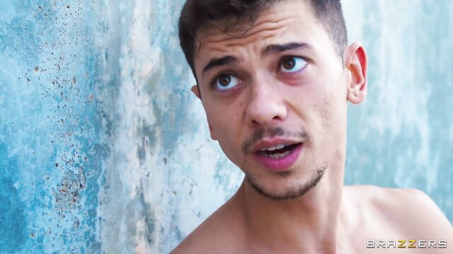 Handsome young Latino man shirtless against blue wall in Brazzers Bubble Butt Booby Trap