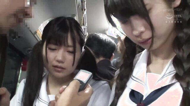 Two cute Japanese college girls in sailor uniforms tease on crowded train