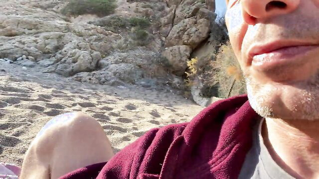 Maya's beach selfie with Thor, rocky shore, maroon towel, sunny day