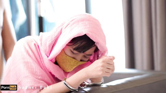 Saanvi Bahl in pink hood, yellow mask, handcuffs on wrists