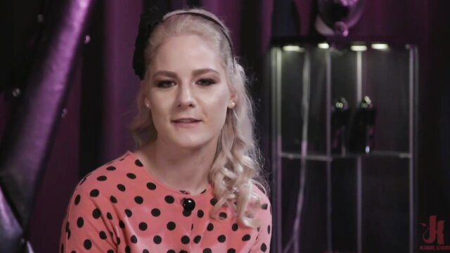 Blonde bombshell in polka dot dress and headband in sultry interview pose