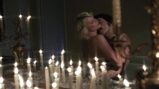 Blonde retro babe passionately kissing nude man in candlelit embrace, 1978 classic