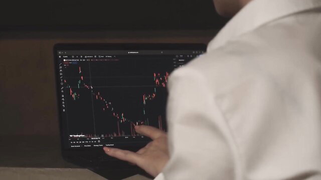 Alexis Crystal in white suit views crashing stocks on screen