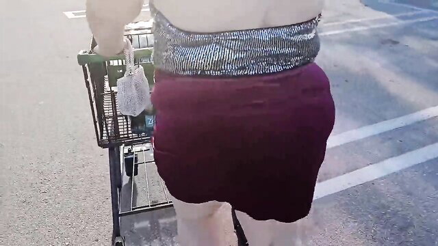 Thick white woman in sparkly top and tight burgundy mini skirt pushing cart in parking lot