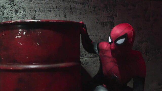 Spidergirl dominated by monster peeking from barrel in dark lair