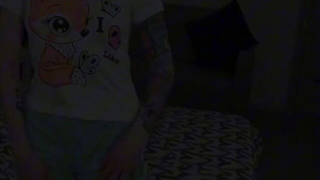 Skinny tattooed girl in kawaii tee and shorts poses seductively