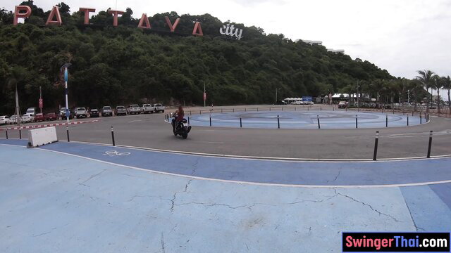 Hot Thai GF rides motorbike by Pattaya City sign, beachside view