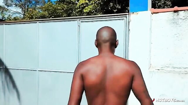 Bald muscular black man shirtless back view in outdoor adult scene