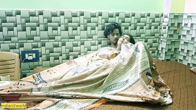 Hot Indian couple cuddling under blanket in bed