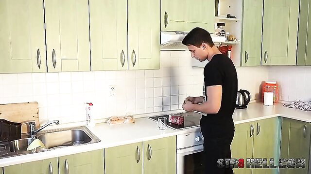 Fit young man in black t-shirt cooking in kitchen, amateur gay tease