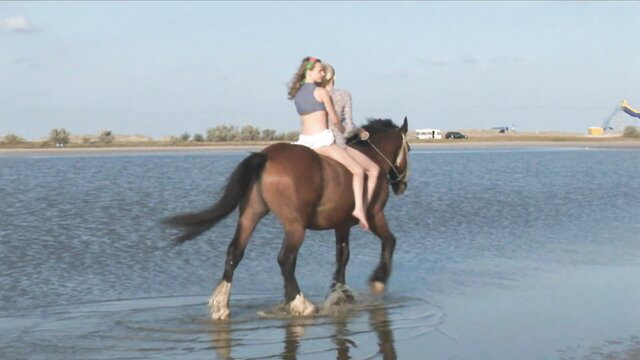Katy rides horse nude in shallow water beach outdoor scene