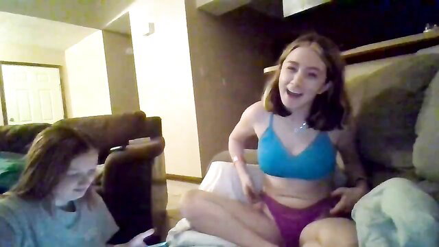 Two smiling teen girls in bikinis lounging on couch amateur style