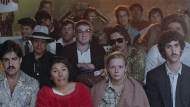 Stiff Competition 1984 cast group shot at packed event, mixed crowd