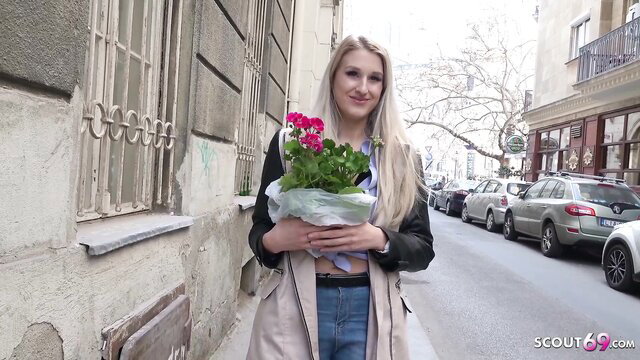 Hot blonde holds pink flowers on street, sexy outdoor tease