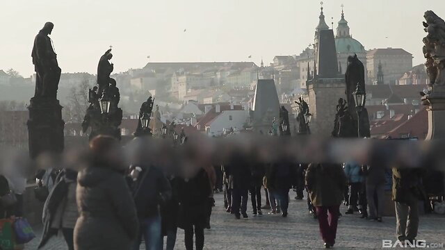 Crowded Prague bridge with statues, blurred crowd in foreground