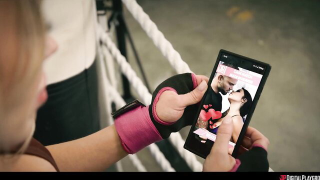 Blonde fighter watches couple kissing on phone in cage fighting trailer