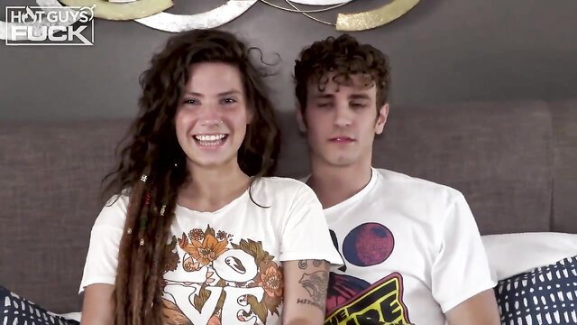 Indica Flower smiles with curly haired guy on bed in tight tops