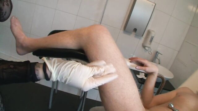 BDSM sub bound on gyno chair, gloved dom spreads shaved pussy legs