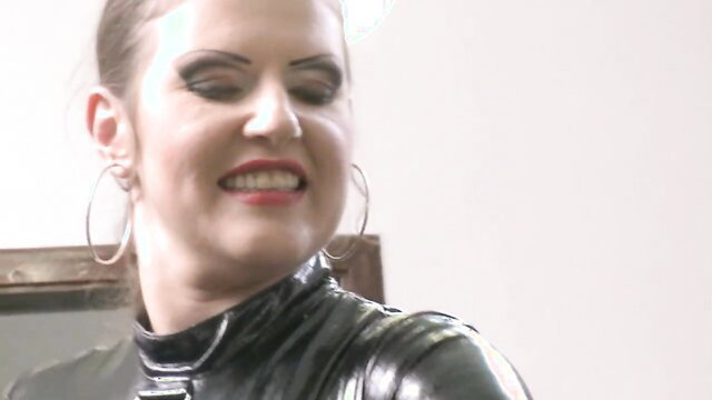 Jessika Girl in shiny latex catsuit smirking dominantly, Obey slave BDSM