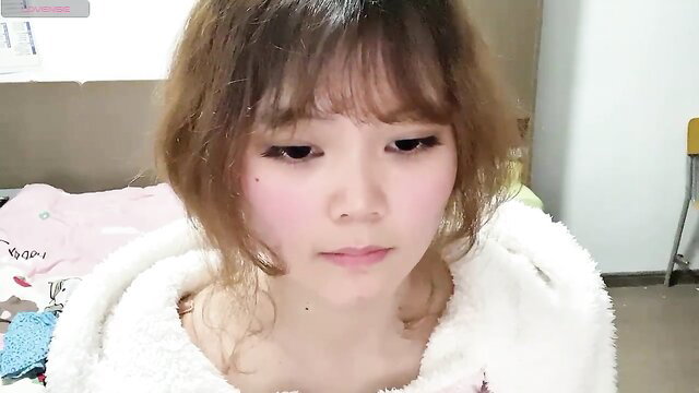 Cute Asian sissieoz in fluffy robe on webcam, soft teasing gaze