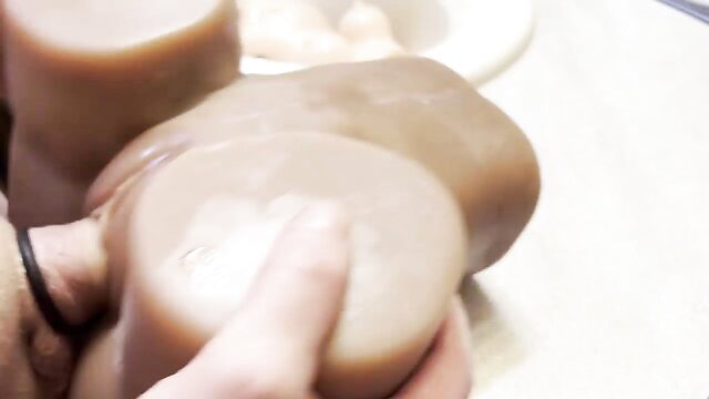 Hand groping huge flesh-toned sex doll tits closeup