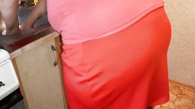 Curvy colleague in tight pink dress bends over sink at work lunch prep