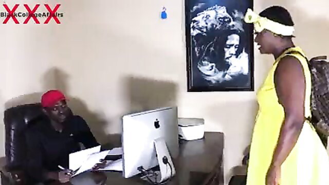 Black college girl in yellow dress stands before man at desk in hardcore scene