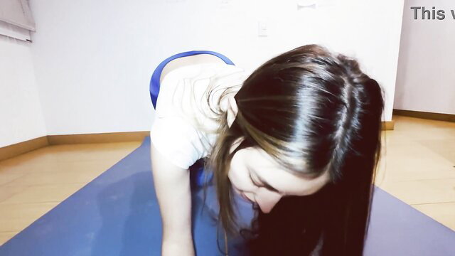 Fit Asian wife in tight yoga pants doing downward dog for trainer