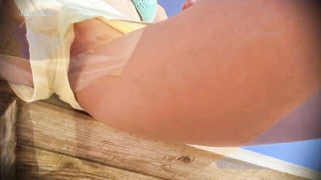 Hidden upskirt view of sexy nude pussy under short shorts on beach