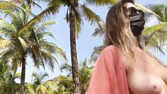 Batty Lux walking topless on beach, big tits, wavy blonde hair, sunglasses mask