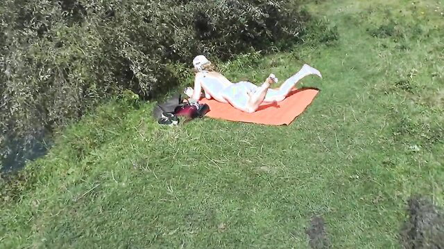 Beautiful blonde MILF sunbathing naked on wild river bank nudist beach