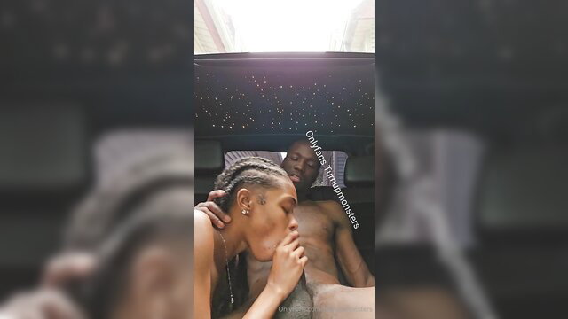 Black woman with braids kissing black man's cock in car