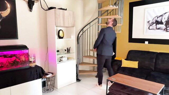 Man in suit looking up spiral stairs in living room, amateur setup