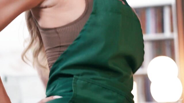 Hot blonde barista in green apron and tank top, teasing from behind