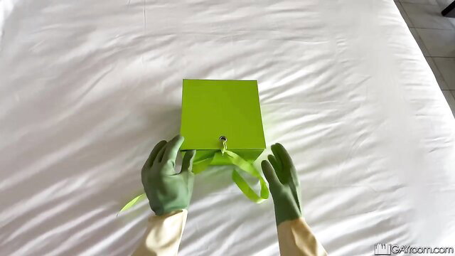 Gloved housekeeper hands unwrap green gift box on bed lingerie surprise