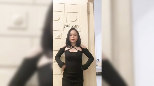 Asian beauty in sexy black crisscross dress poses seductively at door