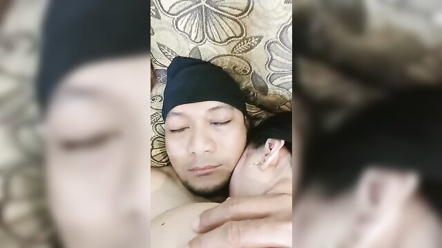 Indonesian milf cuddling nude Asian guy in bed, intimate closeup