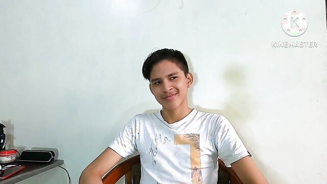 Young smiling Asian twink in white shirt sits casually in gay amateur video thumbnail